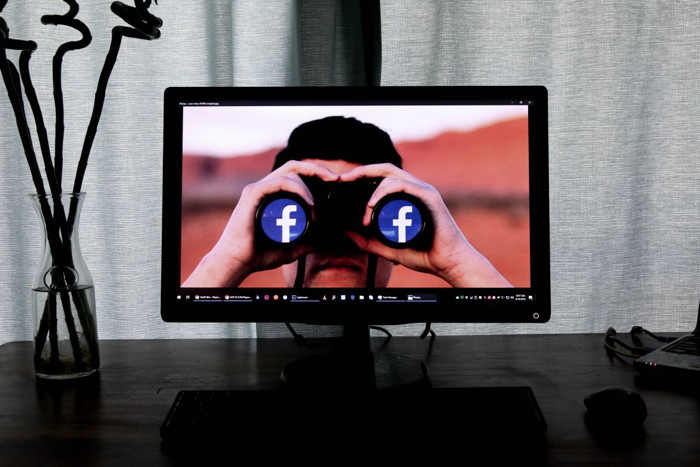 Man with Facebook binoculars on a computer screen
