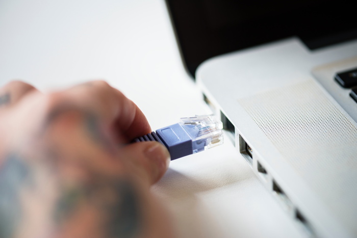 person attaching RJ45 cable on white laptop - Photo by rawpixel on Unsplash