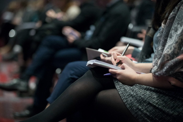 A woman taking notes during a conference - Unsplash
