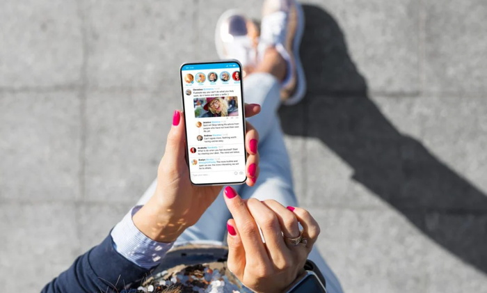 Mujer usando una aplicación de microblogging de redes sociales en su teléfono inteligente - Fuente Travelboom Marketing